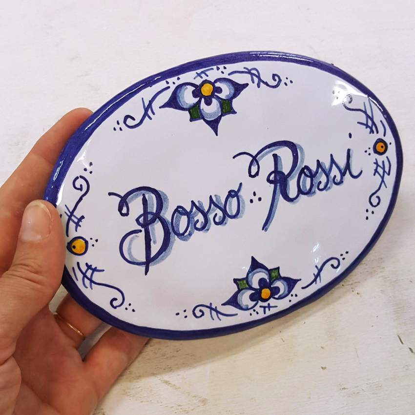 Produzione targhe e insegne fatte a mano. Targa, insegna in ceramica dipinta a mano ovale.
Disegno personalizzato su misura a Bologna.