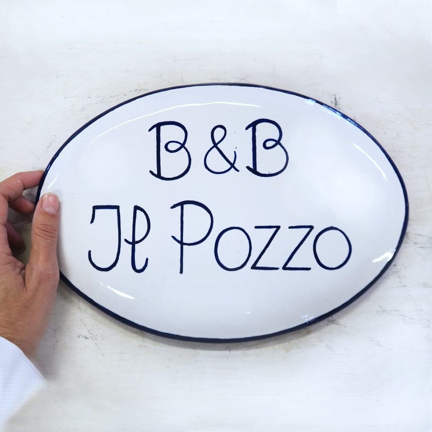 Produzione targhe e insegne fatte a mano. Targa, insegna in ceramica dipinta a mano ovale.
Disegno personalizzato su misura a Bologna.